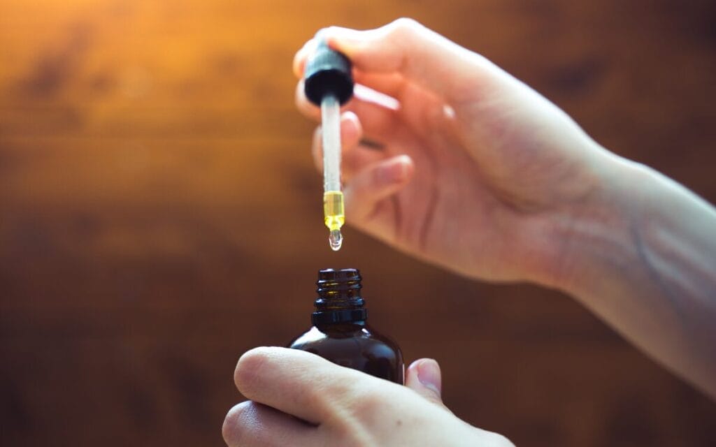 Pipette mit Öl über Flasche halten