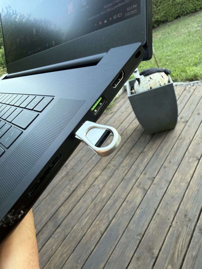 USB-Stick steckt im Laptop auf Holzterrasse.