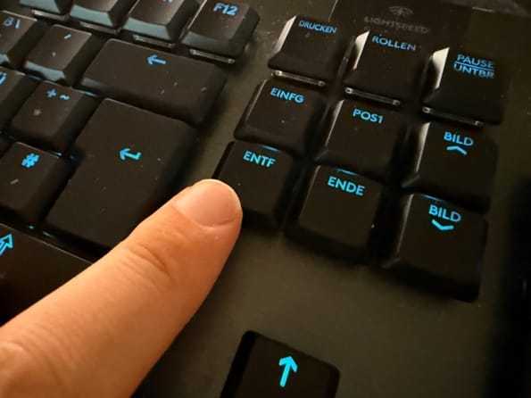 Finger drückt Entf-Taste auf Tastatur
