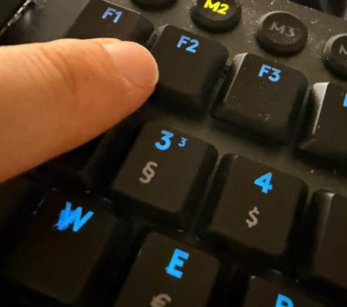 Finger drückt F2 auf Tastatur.