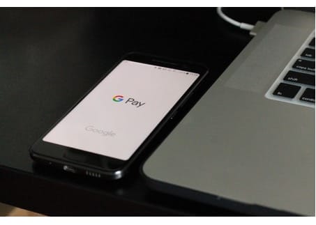 Smartphone with Google Pay next to laptop