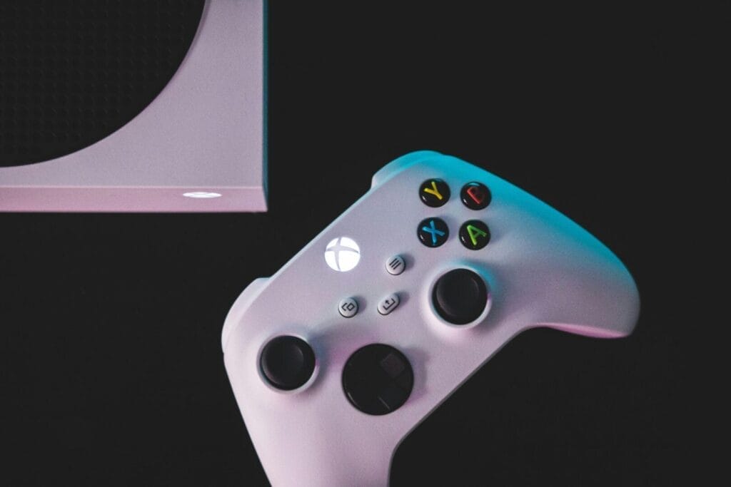 Weißer Gaming-Controller und Konsole auf dunklem Hintergrund.