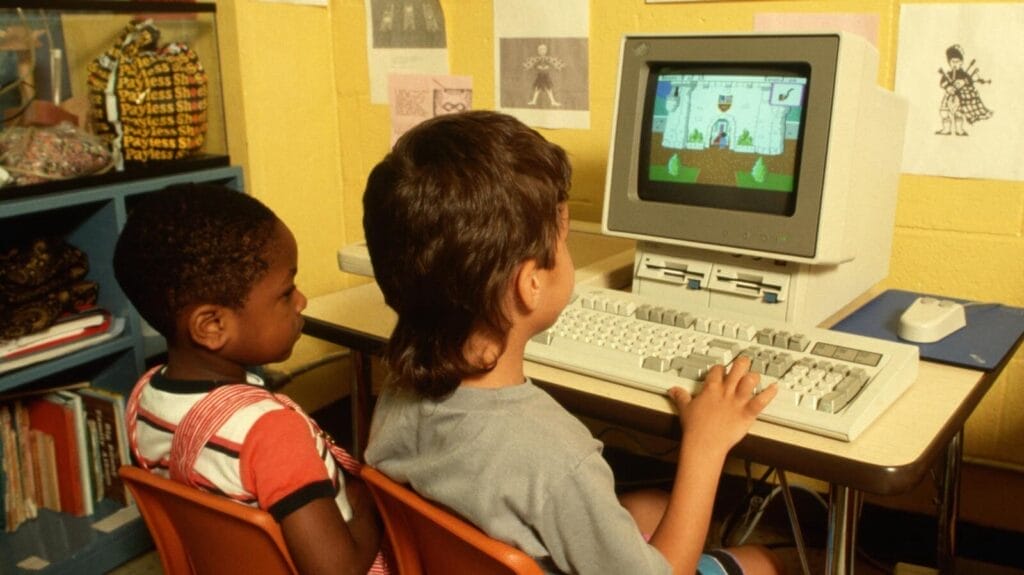 Kinder spielen am alten Computer im Klassenzimmer